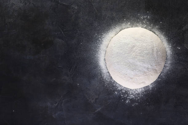 fresh dough for making pizza and bread on the table black background. Top view, copy space for your text, meru, recipe.