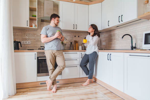 istock smiling man with woman at kitchen drinking tea 1152134954