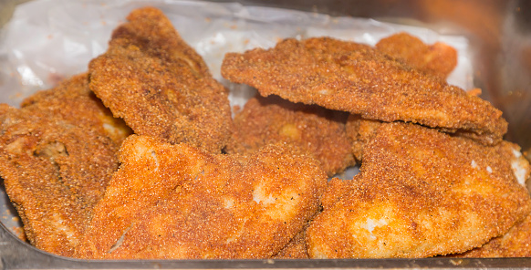 Batch of fried tilapia hot out of the grease for sale or serving at a restaurant deli.