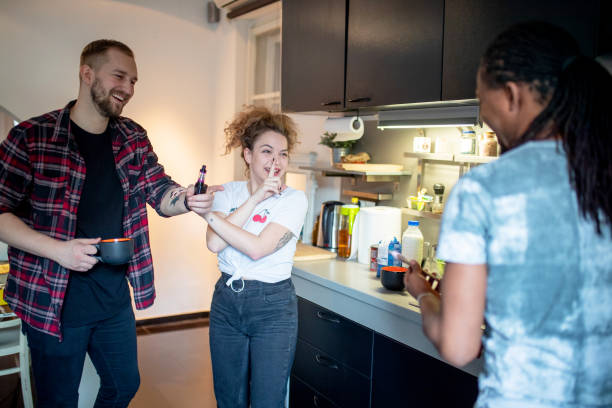 istock Young man holding mug and electronic cigarette laughing with roommates in the kitchen 1152136975