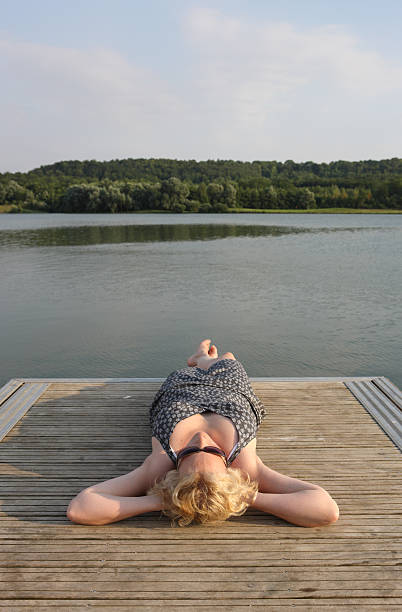 Woman is wearing straw hat looking on the beautiful lake
