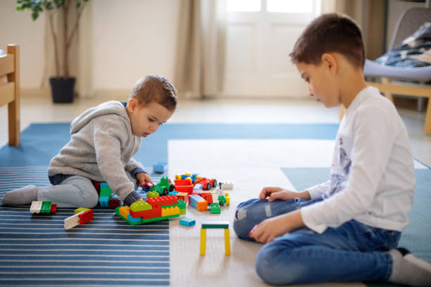 istock Little boy with elder brother playing with toy blocks on the floor 1152139871