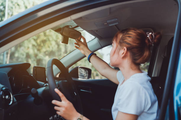 安全運転女性は、旅行旅行を開始する前に、内部の車のバックミラーを調整します。 - driver ストックフォトと画像