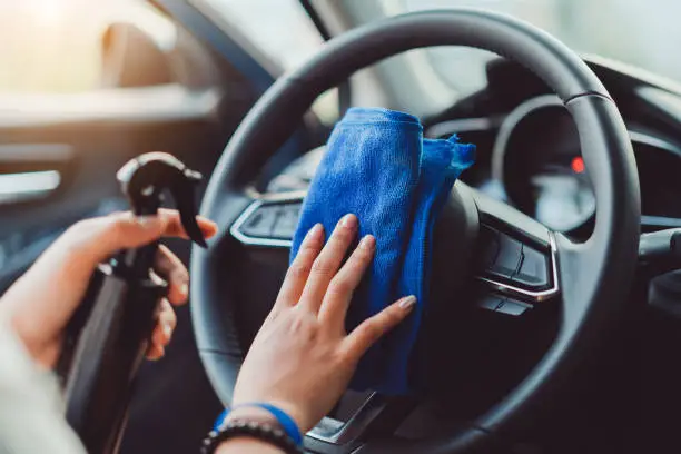 Photo of Professional hands of woman cleaning steering wheel and console car using microfiber cloth protection in interior for shiny after wash a car and vacuum cleaner.