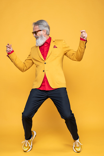 Portrait of senior man wearing yellow jacket on yellow background. Styled, well dressed man.