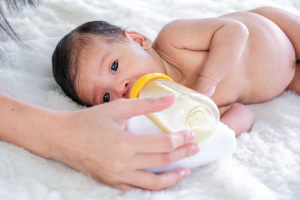 istock Babies on a white prom bed are sucking milk in a bottle. 1152143113