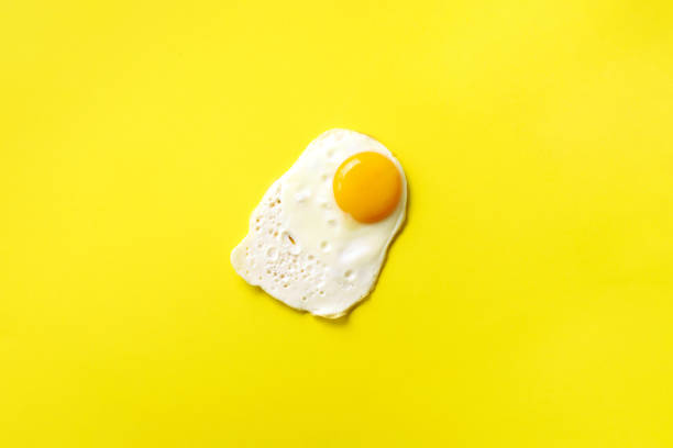 istock One fried egg on yellow paper background. Creative food concept in minimal style. Top view 1152147143