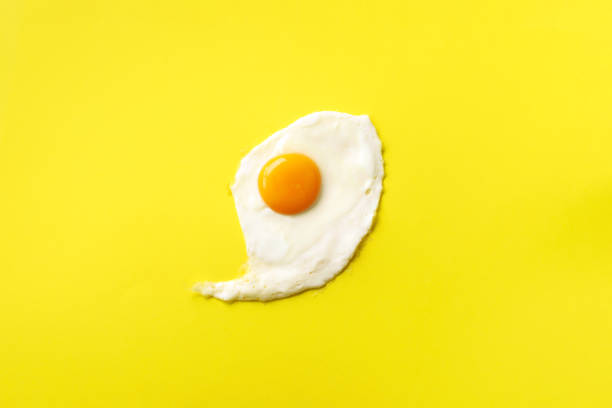 istock One fried egg on yellow paper background. Creative food concept in minimal style. Top view 1152147157