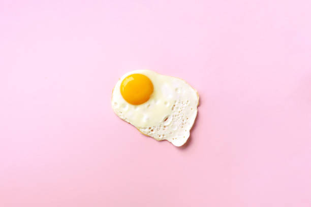 istock One fried egg on pink paper background. Creative food concept in minimal style. Top view 1152147158