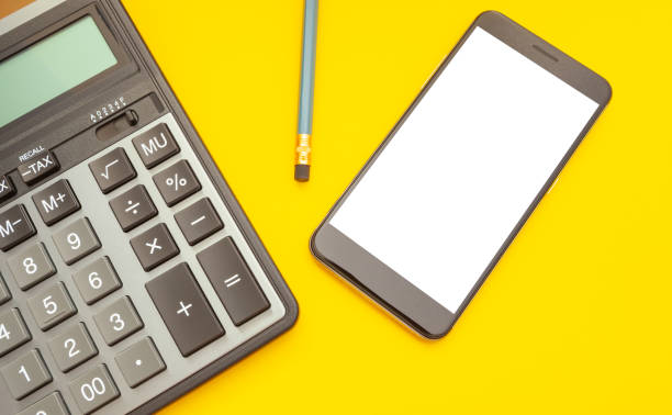 istock Modern calculator and phone with space for text on a yellow background, top view 1152152240