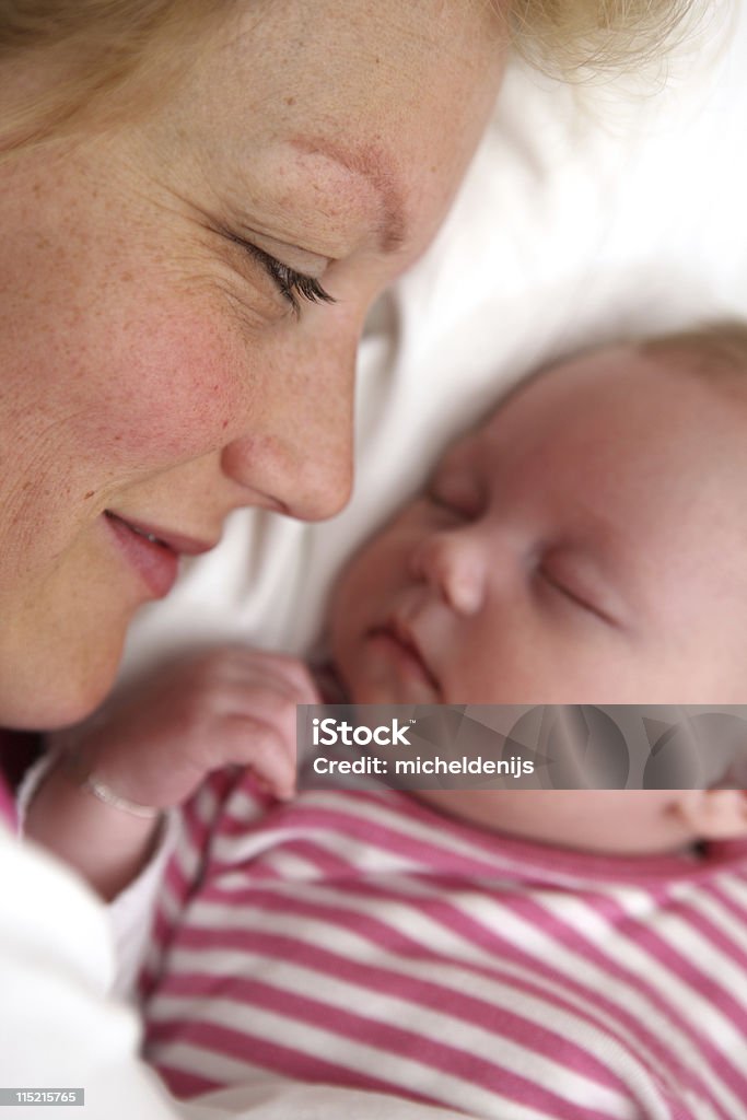 Young Mother Looking At Sleeping Baby Girl Smiling young mother looking at her one month old newborn baby girl. Focus on the mother. Canon 1Ds mark III. 0-1 Months Stock Photo