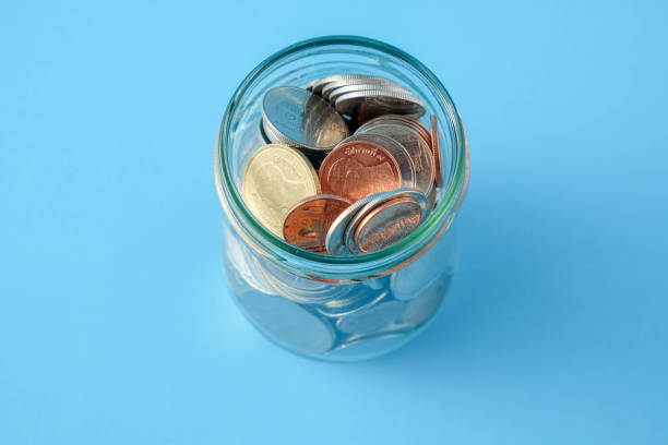istock High Angle View Of Coins In Glass Jar On Blue Background 1152158434