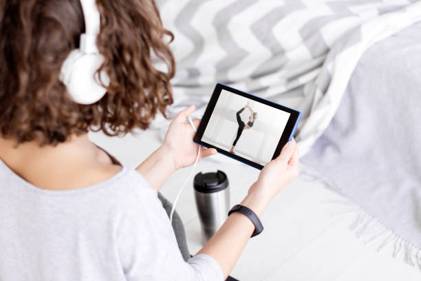 female in headphones watching yoga master class - self improvement audio imagens e fotografias de stock