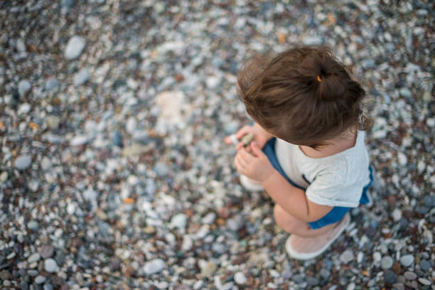 beautiful dreaming meditative healthy little kid sitting in yoga pose on summer sea beach with boat and copy space during holiday vacation
