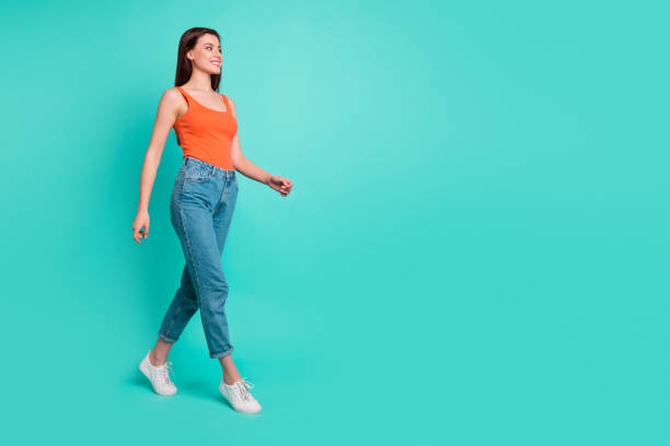 istock Full length side profile body size photo beautiful her she lady wondered look empty space weekend walking park wear casual orange tank-top jeans denim isolated bright teal turquoise background 1152165926