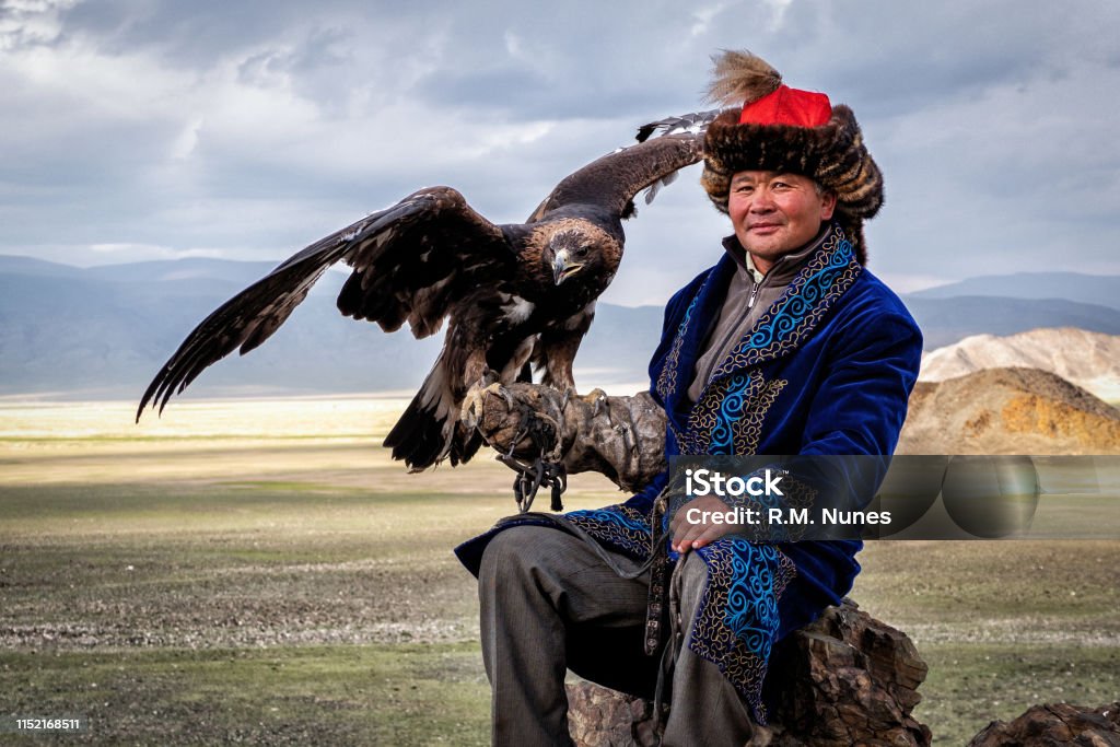 Eagle Hunter with His Eagle in Bayan Olgii, West Mongolia Eagle Hunter with his golden eagle in Bayan-Olgii, West Mongolia. Hunting with eagles is a traditional form of falconry found throughout the Eurasian Steppe. Kazakhstan Stock Photo