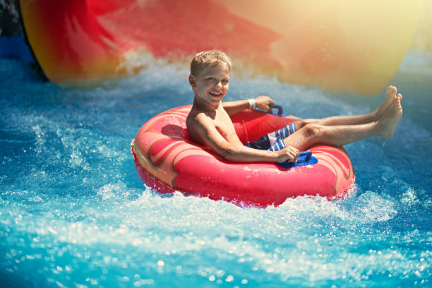 petit garçon appréciant l’eau glissent dans le parc aquatique - inflatable slide sliding child photos et images de collection