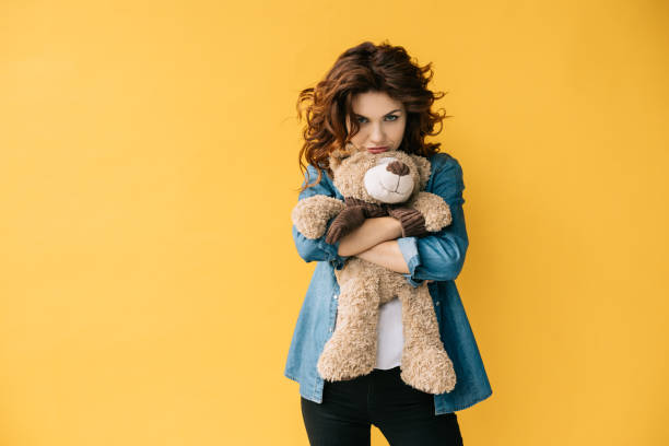 istock upset curly redhead young woman holding teddy bear on orange 1152171733