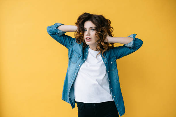 istock surprised curly woman looking at camera while touching red hair on orange 1152171805