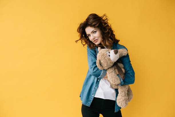 istock attractive redhead girl hugging teddy bear and looking at camera on orange 1152171819