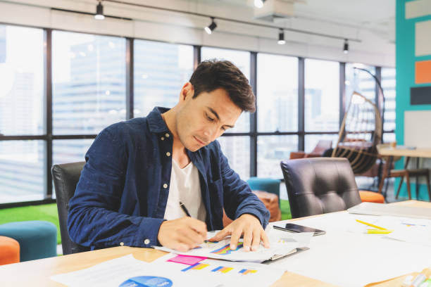 istock Handsome businessman in eyeglasses is making notes and smiling while working with a laptop at home. 1152171943
