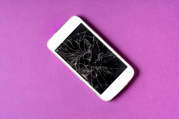 istock Broken mobile phone with cracked display on purple background. 1152173316