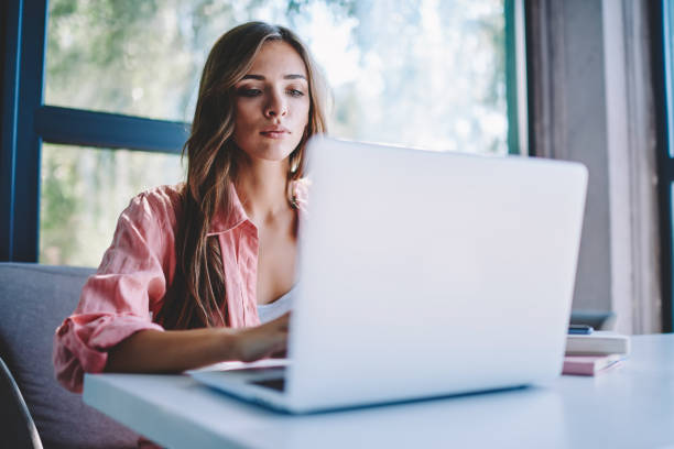istock Concentrated young woman searching information on internet websites for course work using modern laptop with wireless connection in cafe.Pensive female freelancer working at netbook in coworking 1152177485
