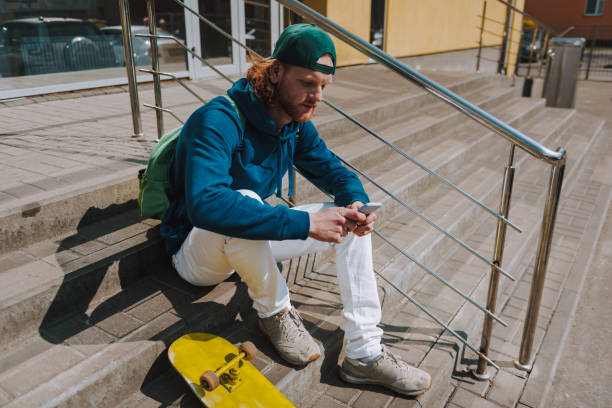 istock Skater man messaging on mobile phone on stairs 1152185513