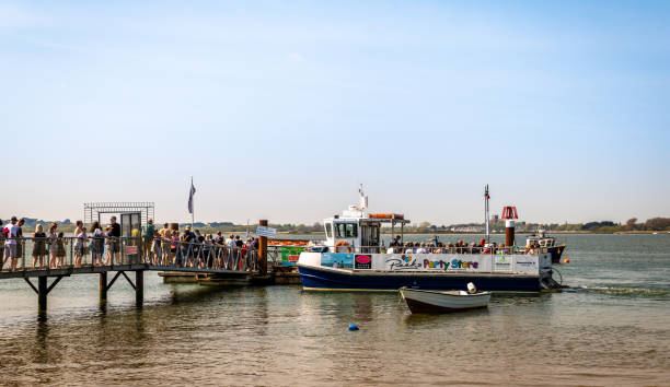 Queuing for the Mudeford Ferry in Christchurch Christchurch, UK - April 21 2019: Queue of people waiting for a passenger ferry boat in Christchurch Harbour in Dorset. christchurch england photos stock pictures, royalty-free photos & images