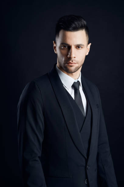 istock Handsome confident man in black suit on dark background 1152186199