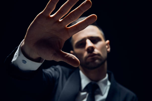istock Handsome man showing stop sign isolated on dark background 1152186210