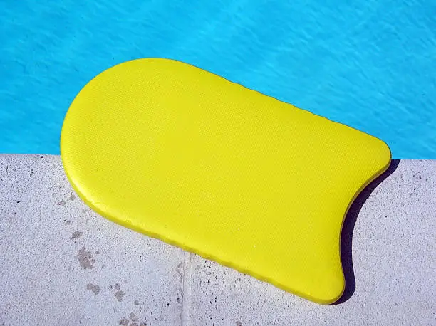 Yellow kickboard on the side of the swimming pool