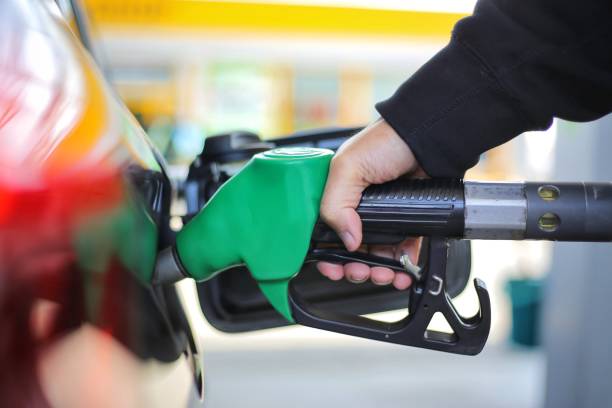 關閉手拿著綠色汽油燃料噴嘴和是填充油箱的黑車在加油站概念的全球化石燃料消耗。 在不久的將來被替代能源取代 - future 個照片及圖片檔
