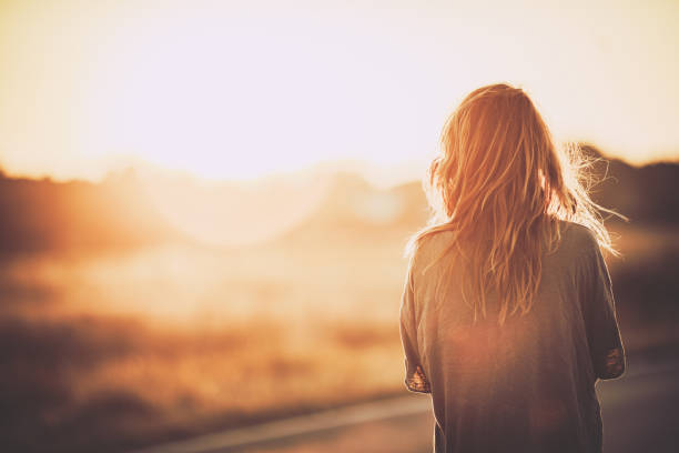 Rear view of a carefree woman looking at sunset in nature. Copy space.