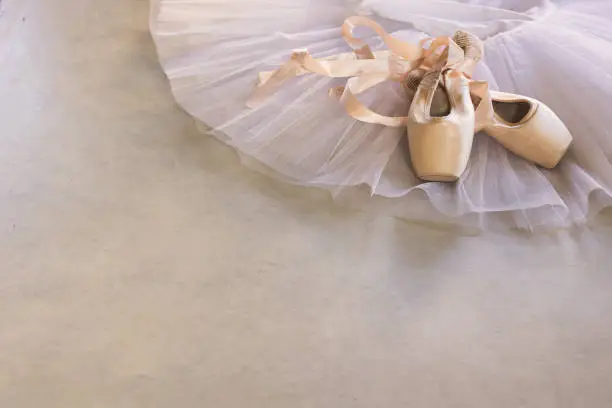 white tutu and pointe shoes on a grey concrete floor, copy space