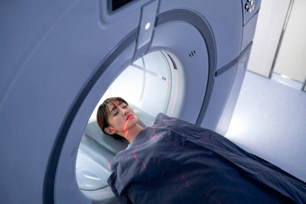 High angle view of patient lying for MRI scan High angle view of patient lying for MRI scan. Sick young woman is going through medical procedure. She is with eyes closed. cat scan stock pictures, royalty-free photos & images
