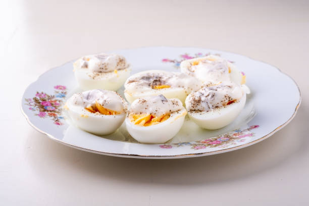 istock Sliced boiled eggs with mayonnaise and pepper in white plate isolated angle view 1152194194