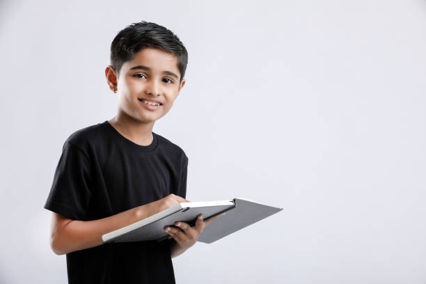 ein kleiner indischer/asiatischer junge mit buch auf dem kopf - reading and writing little boys reading asian ethnicity stock-fotos und bilder