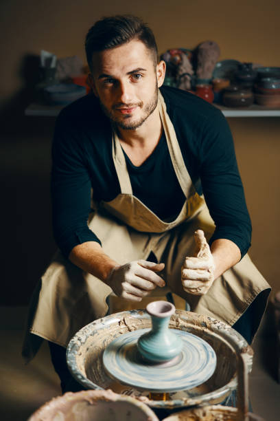 istock Smiling handsome man showing handmade ceramic pot at pottery workshop 1152196558