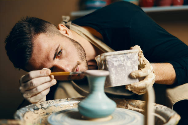 mann malte handgemachte keramik in der keramikwerkstatt - keramiker stock-fotos und bilder
