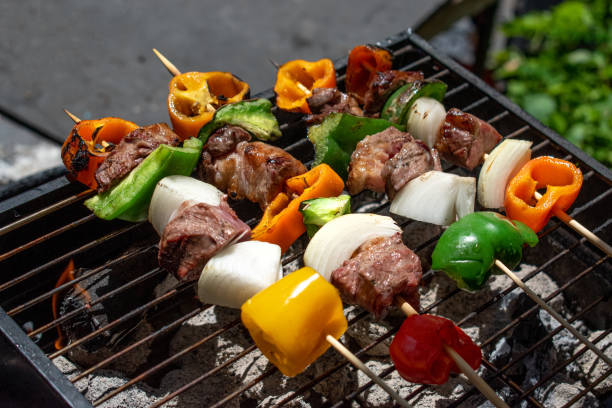meat and vegetable kabobs over charcoal being grilled outdoors stock photo