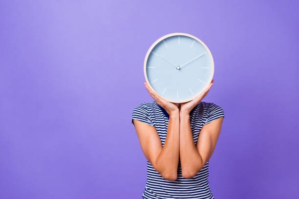 portrait charmant mignon drôle adolescent adolescent heures supplémentaires manqué université avenir femme d’affaires entrepreneur pause matin concept cacher tête rayé t-shirt jeunesse vêtements isolé violet fond - clock face clock time deadline photos et images de collection