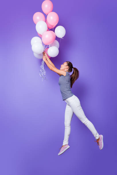 istock Vertical full length body size profile side view of her she nice-looking attractive cheerful cheery girl having fun flying with helium balls isolated over violet purple vivid shine bright background 1152196767