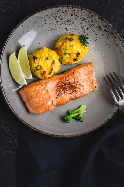 istock Grilled Salmon Fillets with Saffron Risotto and Lime on Dark Background 1152196793