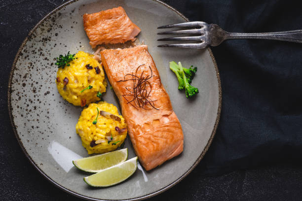 istock Grilled Salmon Fillets with Saffron Risotto and Lime on Dark Background 1152197377