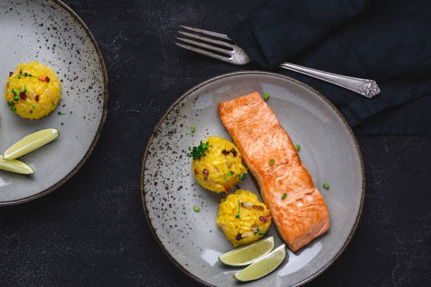 istock Grilled Salmon Fillets with Saffron Risotto and Lime on Dark Background 1152197410