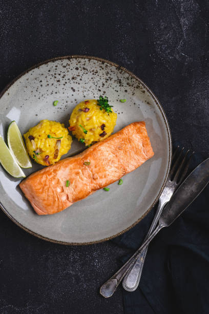 istock Grilled Salmon Fillets with Saffron Risotto and Lime on Dark Background 1152197449