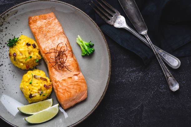 istock Grilled Salmon Fillets with Saffron Risotto and Lime on Dark Background 1152197495