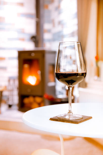 istock Glass of red wine on cozy fireplace background 1152199095