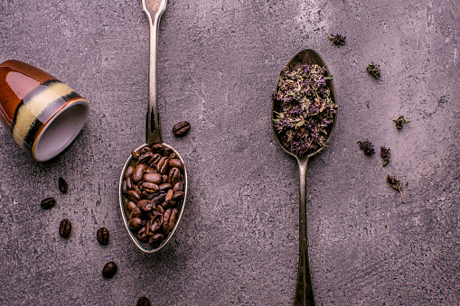 Coffee Beans and Tea in Rustic Spoons over Dark Stone Background